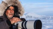 Photographer with a telephoto camera in a snowy Arctic landscape