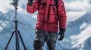 Cinematographer with a camera on a tripod in a snowy mountain setting