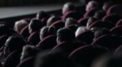 Audience members seated in rows of a dark cinema auditorium