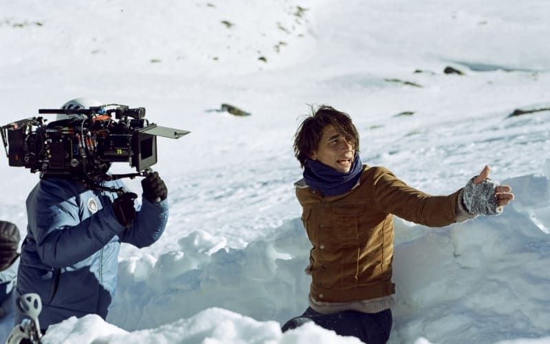 Film crew member and actor working amid snow and bright winter light